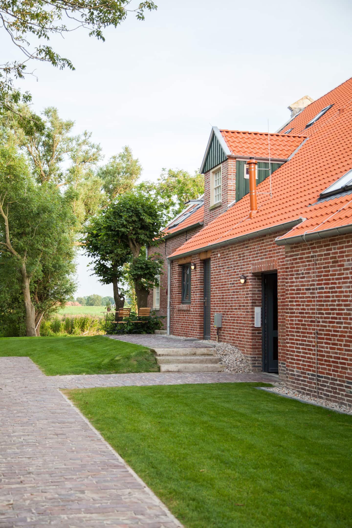 Terrassen und Garten des Gulfhofs, dahinter der Nordseedeich